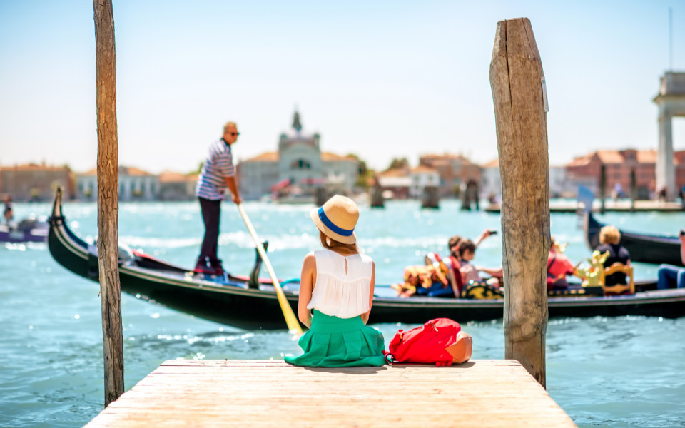 Frau sitzt am Steg in Venedig mit Gondel